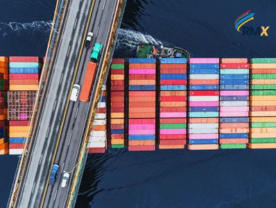Aerial view of a cargo ship passing under a bridge with colorful containers.