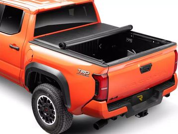 Orange pickup truck with a black truck bed cover rolled up.