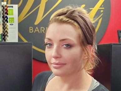 Woman with light makeup and tied-back hair indoors.