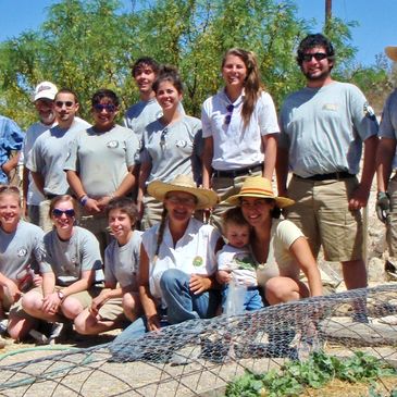 Group of smiling volunteers pose for a group photo in the Terlingua Community Garden