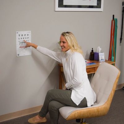 A woman pointing at an eye chart in a clinic.