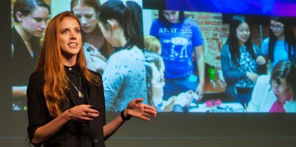 Woman presenting in front of a screen showing a group of people collaborating.
