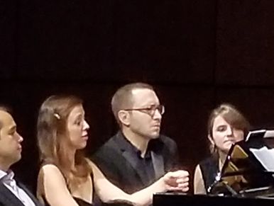 Three musicians focused on playing piano in a concert.