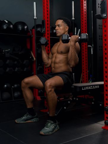 Man doing seated dumbbell shoulder press in gym.
