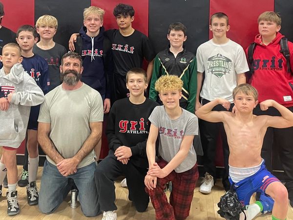 A group of young athletes and their coach posing in a gym.
