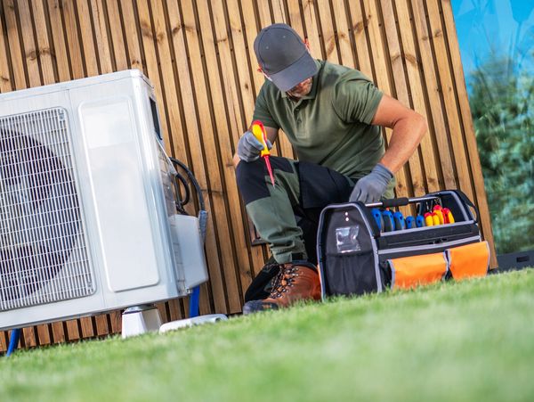 Technician repairing outdoor HVAC unit.