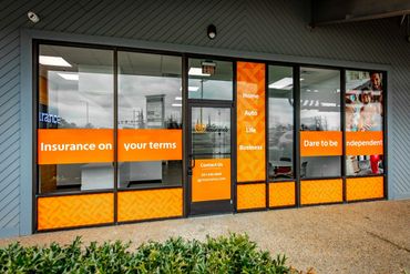 Insurance office with orange-themed window signs promoting personalized coverage options.