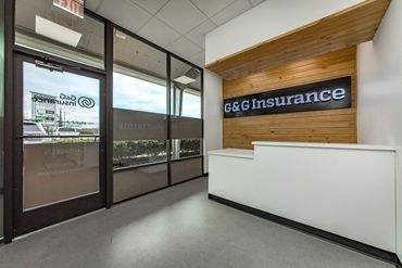 Reception area of G&amp;G Insurance with modern wooden accent wall and glass entrance.
