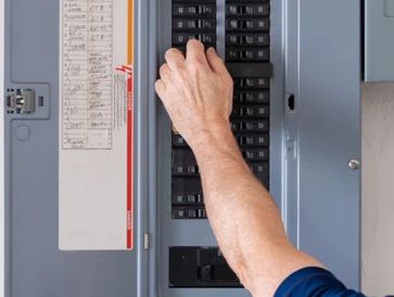 Licensed electrician inspecting an electrical panel box, ensuring safe and code-compliant wiring.