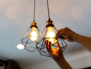 Electrician installing a light bulb and performing lighting installation in a home.