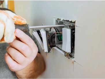 Electrician Installing switches in wall using screwdriver 