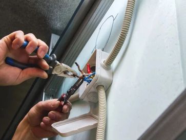 Electrician repairing wiring in clients home using tools 