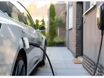 Electric vehicle charging at home with EV charger plugged into car in driveway