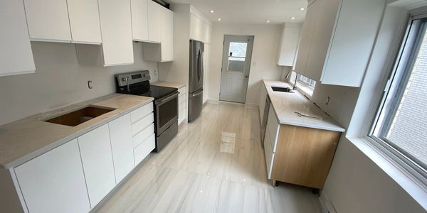 Bright, modern kitchen with white cabinets and marble floors.