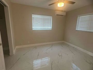 Empty room with marble floor and ceiling fan.