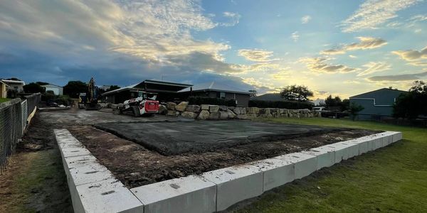 Construction site with concrete blocks and machinery at sunset.