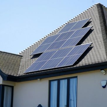 Solar Panels on a black tiled roof with a blue sky in the background.
