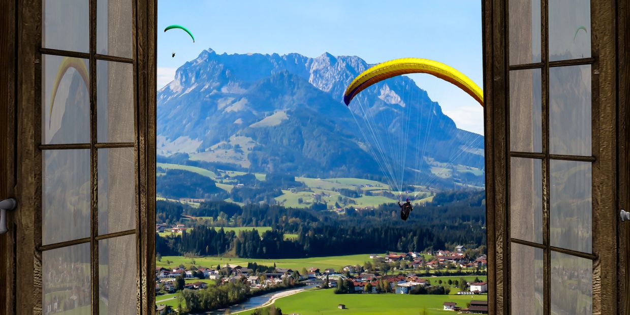Gorgeous vacation in Europe overlooking mountains, paragliding, and a river.