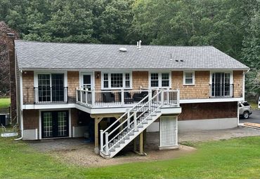 Two-story house with wooden siding and an outdoor staircase to the upper deck.
