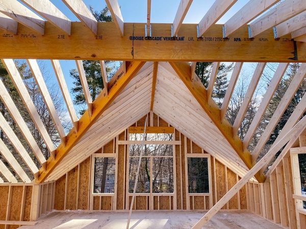 Wooden framing of a house under construction with a vaulted ceiling.