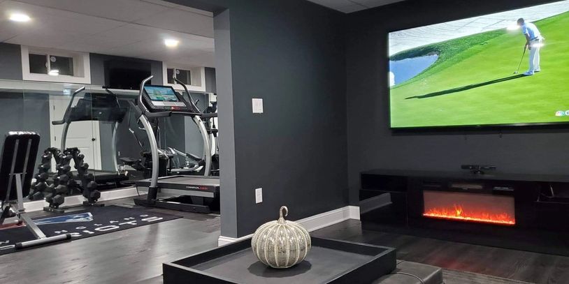 Modern home gym and entertainment area with treadmill, dumbbells, and wall-mounted TV.