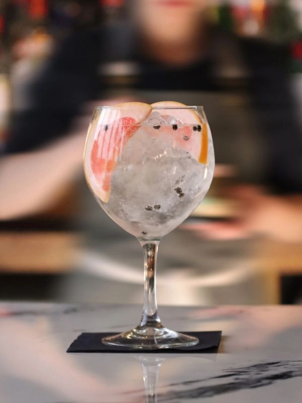 Cocktail with ice and citrus slices in a glass.