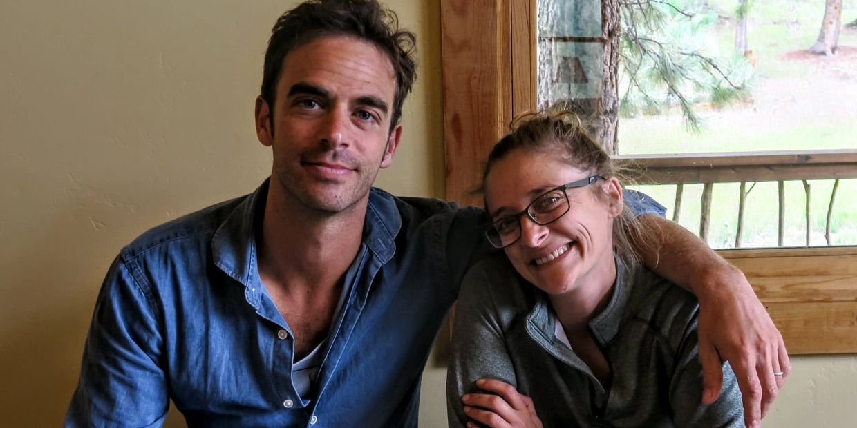 Two people smiling indoors, close together.