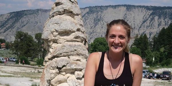 Smiling woman outdoors near rock formation.