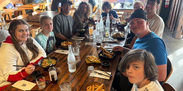Group of friends enjoying a meal together at a wooden table in a cozy restaurant.
