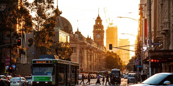 Sunset over a busy city street with pedestrians and a bus.