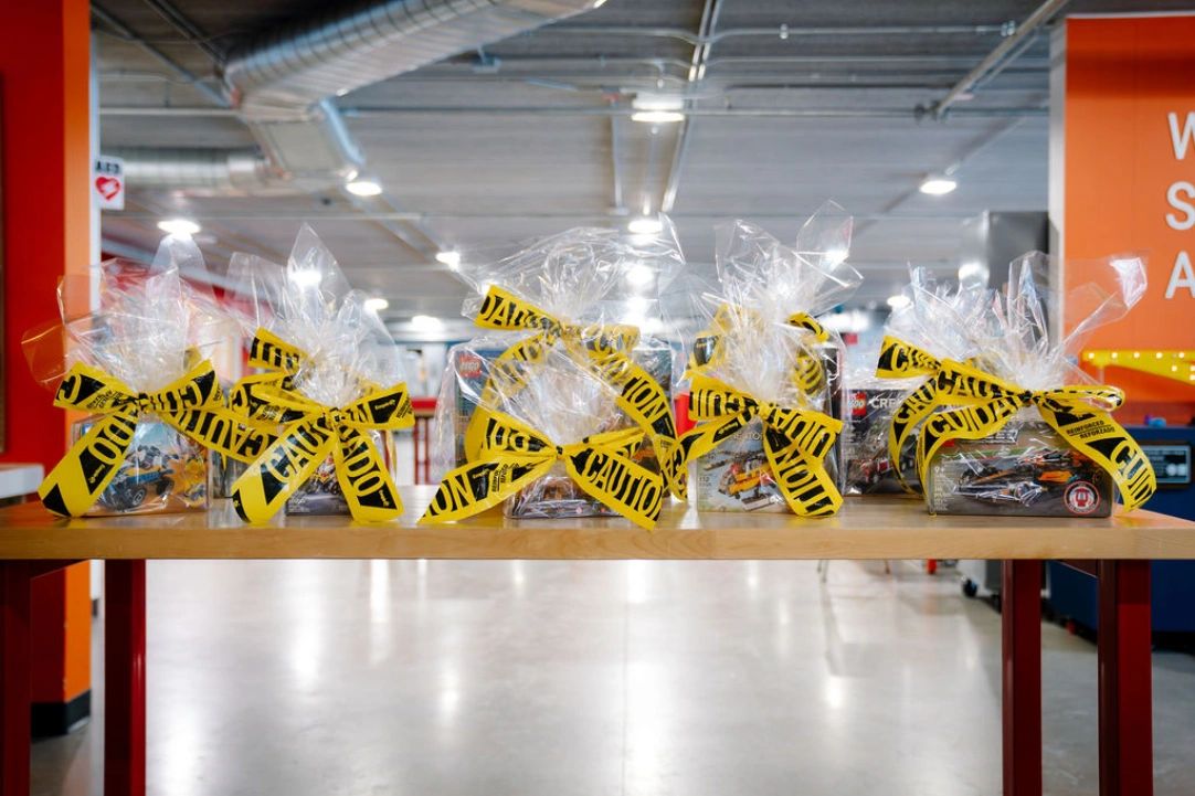 Gift packages wrapped in plastic with yellow caution tape bows on a table.