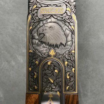 Engraved rifle part with eagle and floral designs.