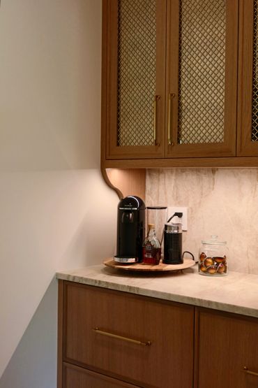 Cozy coffee station with a Nespresso machine and syrup on a wooden tray.