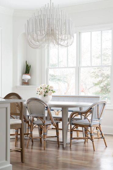 Bright dining room with rattan chairs and a large white chandelier.