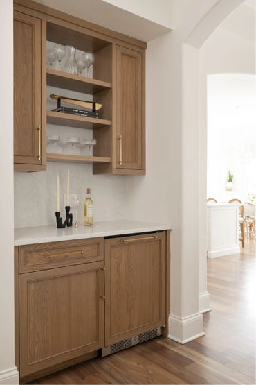 Elegant wooden cabinetry with marble countertop and glassware in a bright kitchen corner.