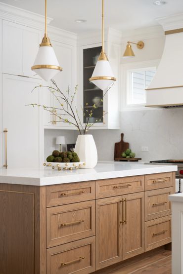 Elegant kitchen island with wooden cabinets and gold-accented pendant lights.