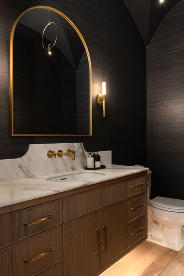 Elegant bathroom with gold accents, dark walls, and marble countertop.
