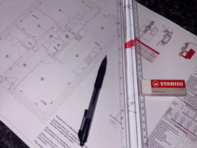 Architectural blueprints with drawing tools and pen on a desk.