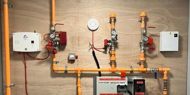 Wall-mounted plumbing system with orange pipes and control units.
