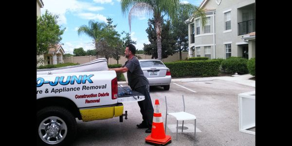 Man loading items into a junk removal truck in a residential area.