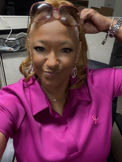 Woman in pink shirt making a playful face with glasses on her head.