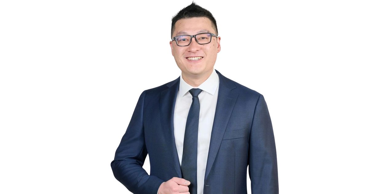 Smiling man in a blue suit adjusting his jacket against a white background.