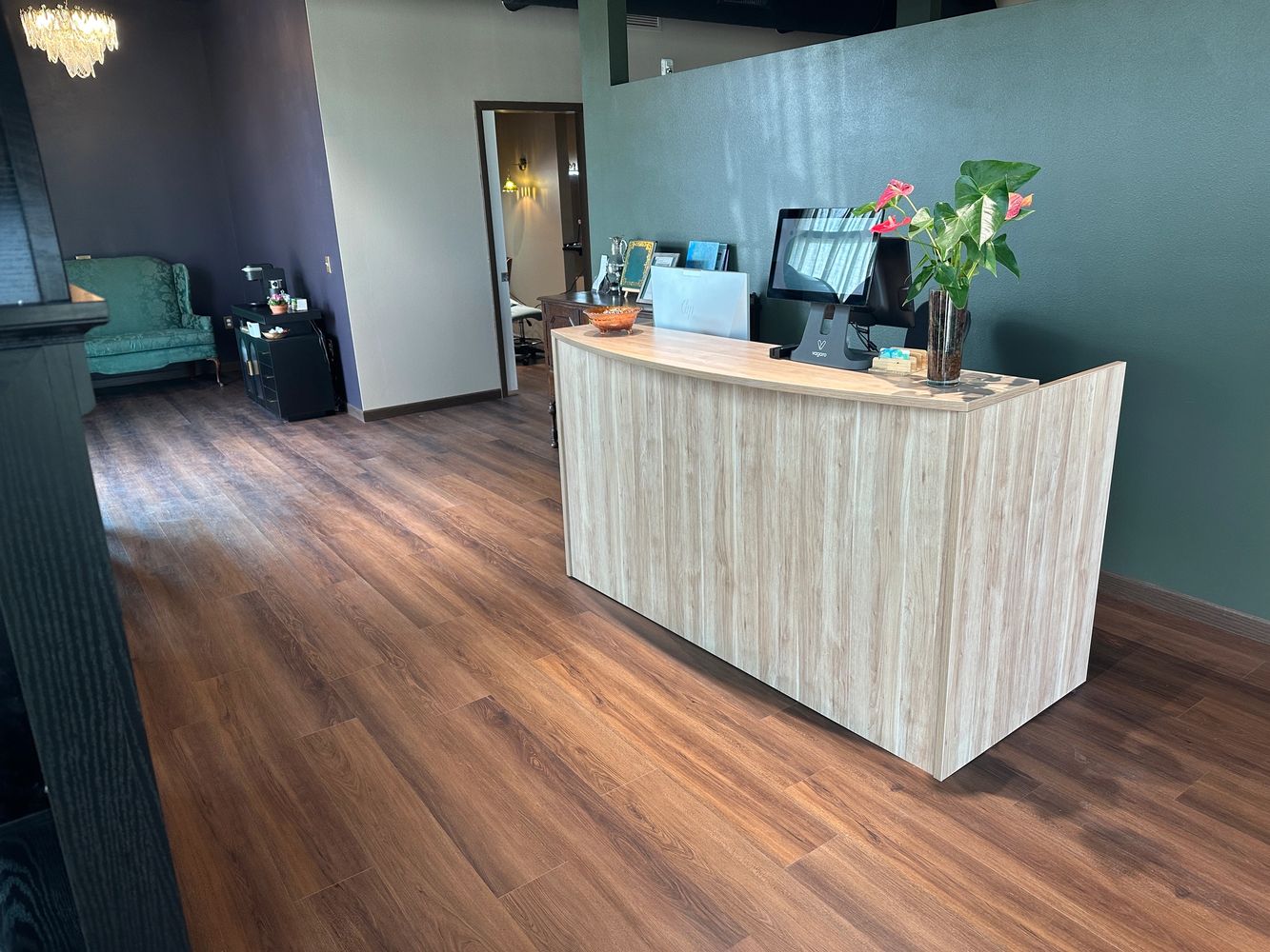 Modern reception area with wooden desk and green accent wall.