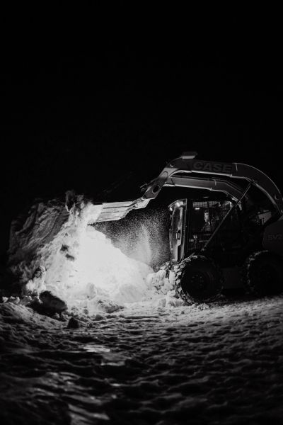 A loader clearing snow at night with dramatic lighting.