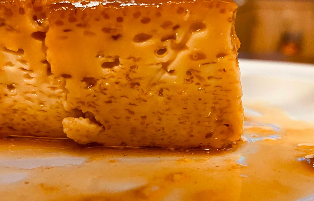 Close-up of caramel flan dessert with syrup on a white plate.