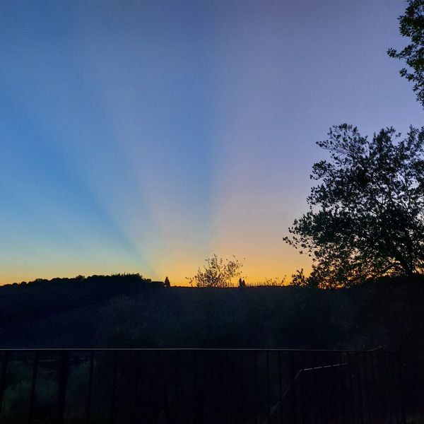 Sunset over rolling countryside hills with a blue, orange, and golden sky