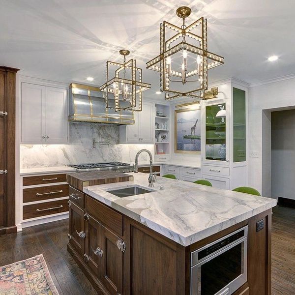 Elegant kitchen with marble countertops and gold geometric pendant lights.