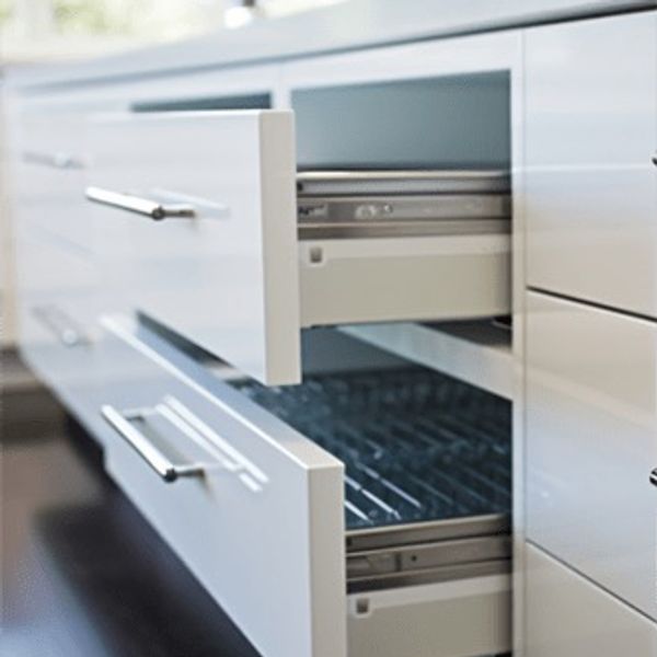 Two open white kitchen drawers with sleek metal handles.