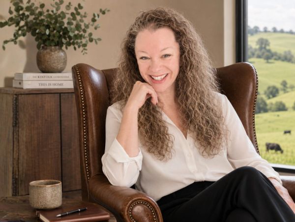 Smiling woman sitting in a leather chair in a cozy room.