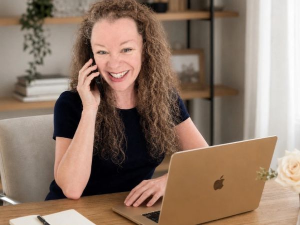 Woman smiling while talking on phone at her desk.